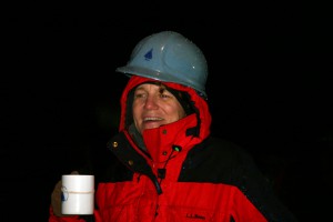 On the rainy deck of the Knorr, Amy Bower, drinking hot chocolate to keep warm, watches, as the mooring slowly unspools. (Photo by David Sutherland, Woods Hole Oceanographic Institution)