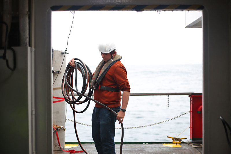 John San Sucie coils a hose on the deck of the R/V Sarmiento de Gamboa. Photo by Markey Parker © Woods Hole Oceanographic Institution